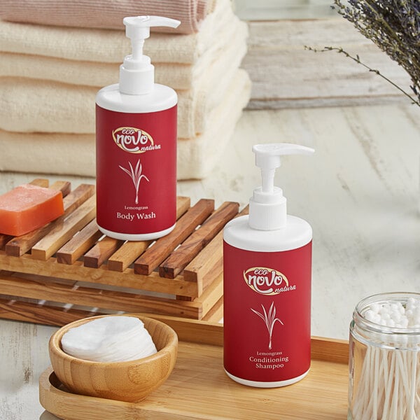 A red and white bottle of Noble Eco Novo Natura conditioning shampoo and body wash with a white pump next to a stack of towels.