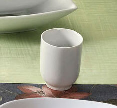 A CAC Super White Porcelain Sake Cup next to a white bowl on a table.