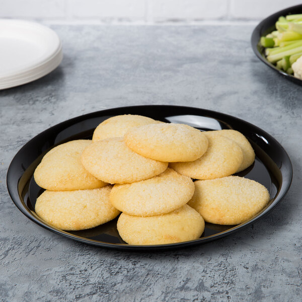A black WNA Comet round catering tray with cookies and celery on it.