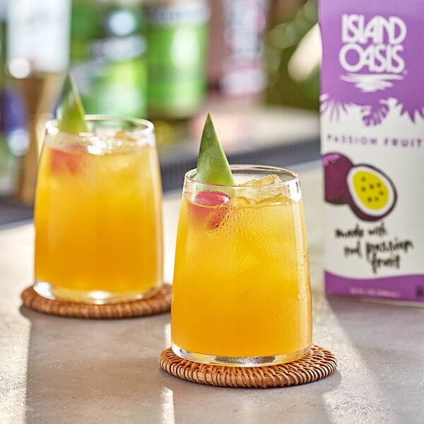 Two glasses of Island Oasis passion fruit drinks with fruit slices on the rim.