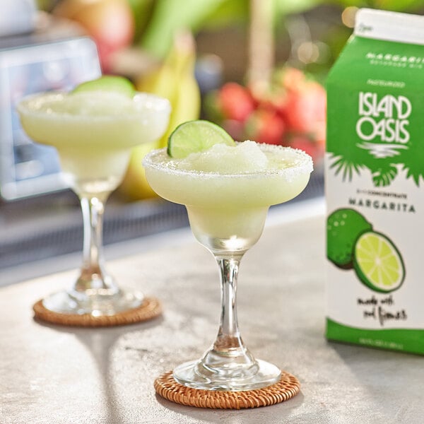 A glass of yellow Island Oasis Margarita mix garnished with a lime.