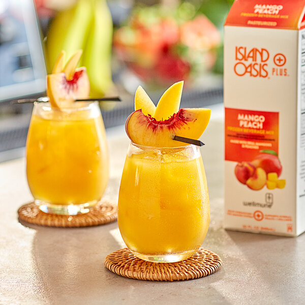 Two glasses of Island Oasis mango peach juice with a slice of peach on top.