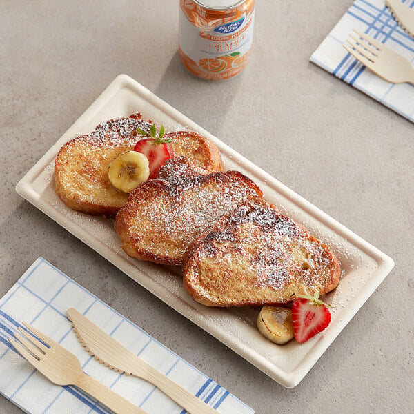 A plate of french toast with bananas and powdered sugar on a table with a wooden fork and knife.