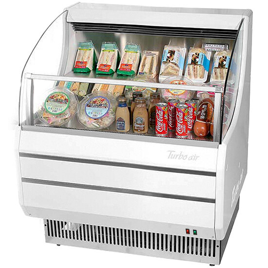 A white Turbo Air slim line horizontal air curtain display case with food and drinks inside.