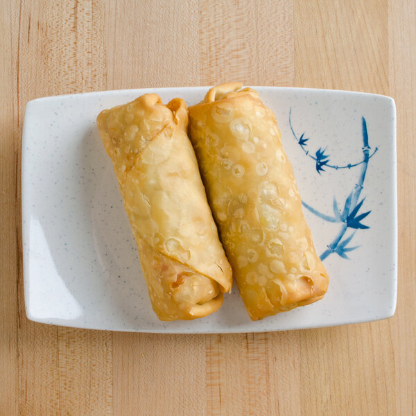 Two fried spring rolls on a Thunder Group Blue Bamboo rectangular melamine plate.