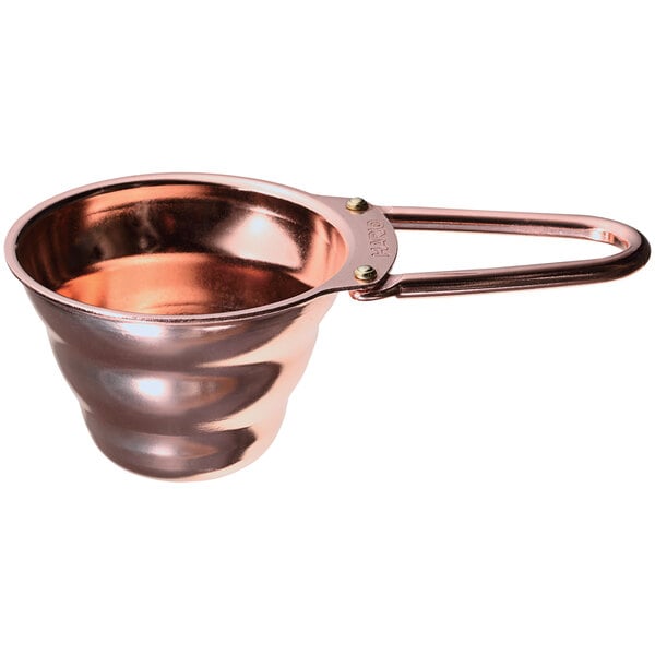 A copper measuring spoon with a handle.