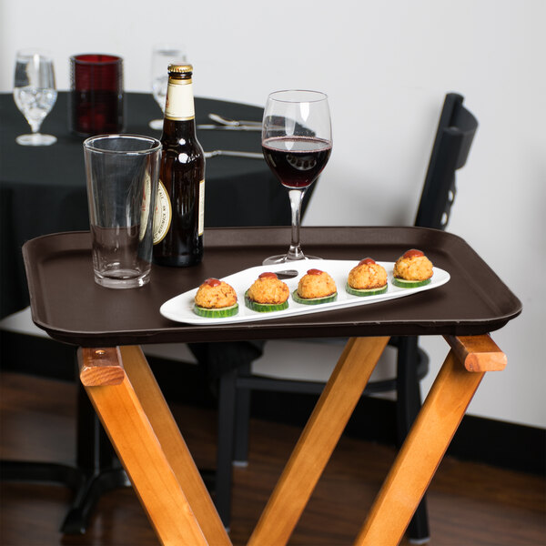 A Cambro Tavern Tan non-skid serving tray with food and wine on it on a table.
