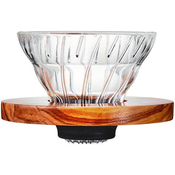 A Hario glass coffee dripper on a wood stand.