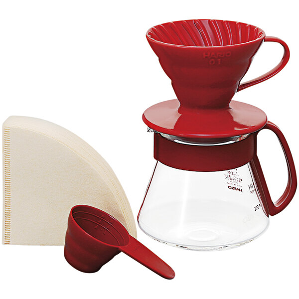 A red Hario V60 coffee dripper with a red measuring spoon and a glass server with a red handle.