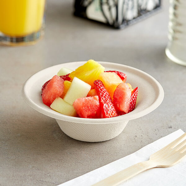 A bowl of fruit in an EcoChoice natural bagasse bowl with a fork on a napkin.
