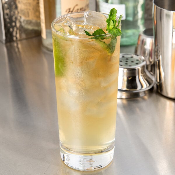 A Libbey tall highball glass filled with liquid, ice, and mint leaves.