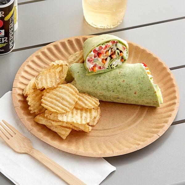 A Choice uncoated paper plate with a burrito, vegetables, and cream cheese on a table with a fork and a glass of beer.