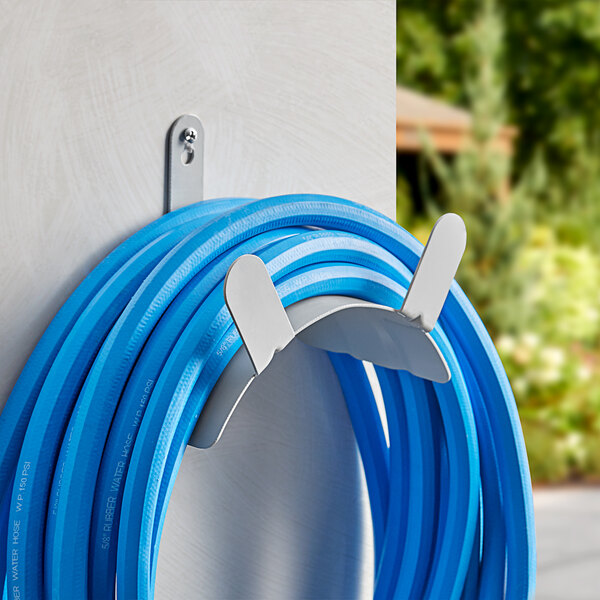 A Lavex Garden Hose Hanger with a blue hose attached to it on a wall.
