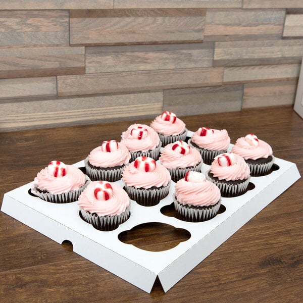 A white Baker's Mark cupcake insert holding 12 cupcakes with pink frosting and candy on top.