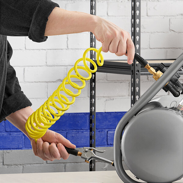 A person using an Assure Parts yellow coiled air/water hose.