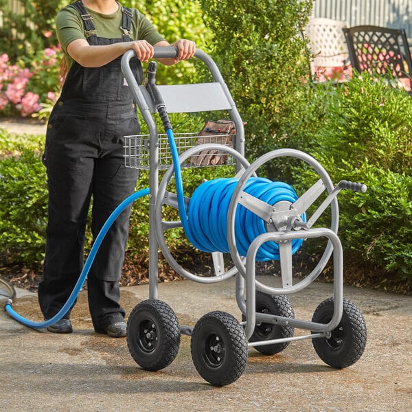A woman standing next to a blue Lavex garden hose reel.