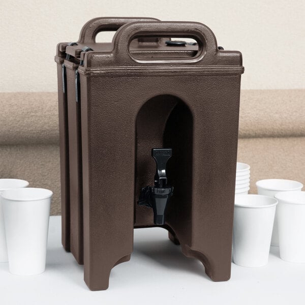 A dark brown Cambro insulated beverage dispenser with a black spigot and white cups.