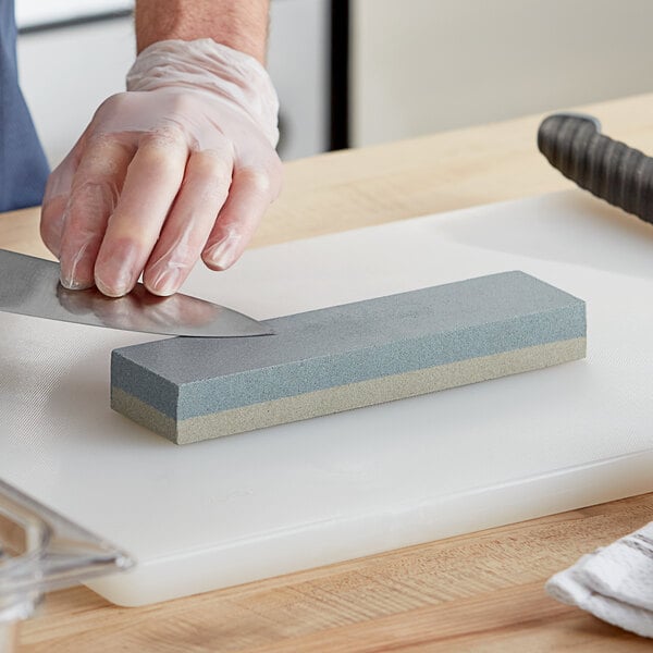 A person using a Choice aluminum oxide knife sharpening stone to sharpen a knife.