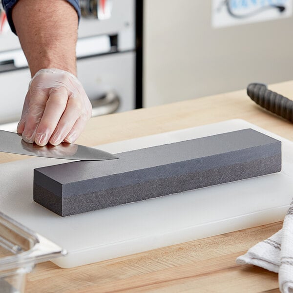 A hand sharpening a knife on a Choice carbonized silicon sharpening stone.