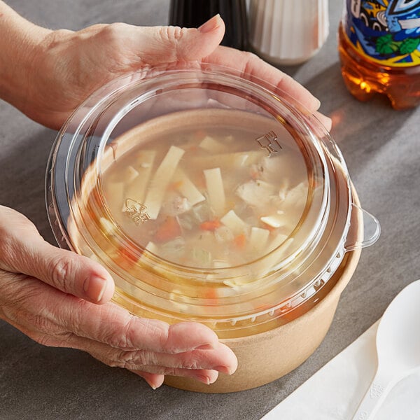 A person holding a Choice plastic container of soup.