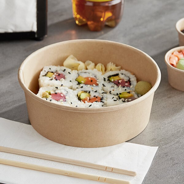 A sushi roll in a Choice round paper take-out container on a table.