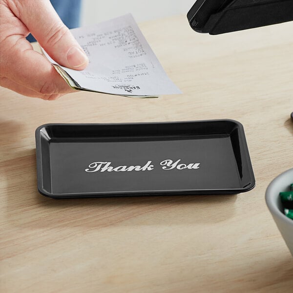 A person holding a black Choice Thank You tip tray with white text.