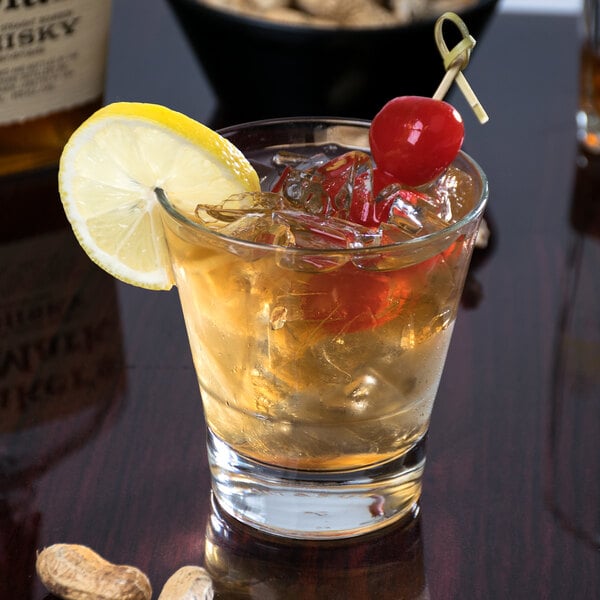 A Libbey stackable rocks glass with a drink, ice, a lemon slice, and a cherry.