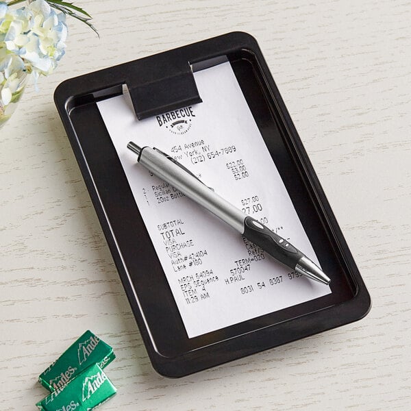 A receipt and pen on a black Choice tip tray with clip.