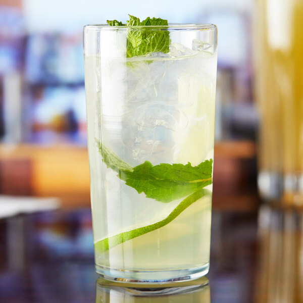 A glass of liquid with a lime and mint leaf in an Anchor Hocking Straight-Sided Collins Glass.