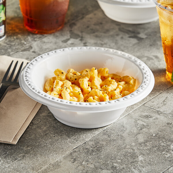 A bowl of macaroni and cheese in a white plastic bowl with a fork.