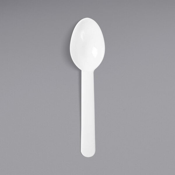 A white plastic spoon on a gray background.