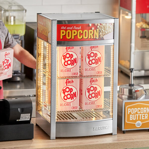 A man using a ServIt countertop display warmer to serve popcorn in a stadium.