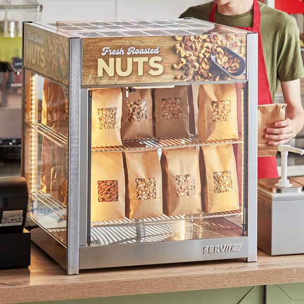 A man standing behind a ServIt countertop display case full of roasted nuts.