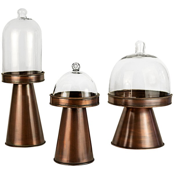 A Kalalou 3-piece copper display stand set with glass domes on top of glass containers.