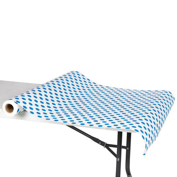 A white table with a blue and white polka dot paper table cover on it.