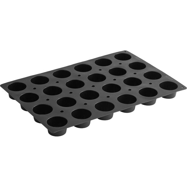 A black de Buyer silicone round muffin pan with holes.