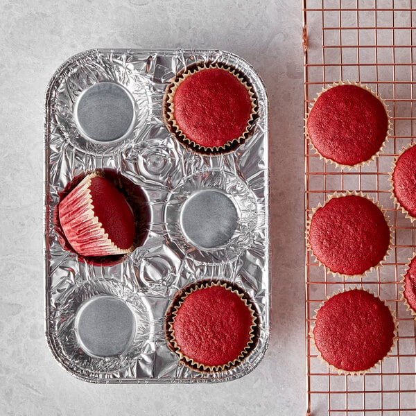 A red cupcake in a D&W Fine Pack foil wrapper on a wire rack.