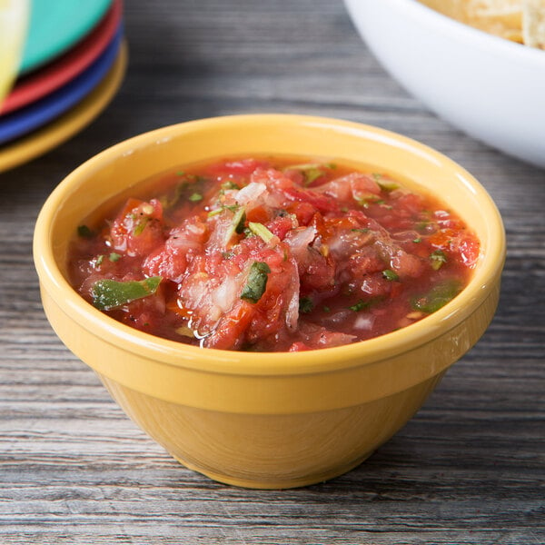 A table with bowls of salsa and chips. A Diamond Mardi Gras melamine bowl filled with tortilla chips.