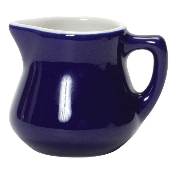 A blue and white ceramic creamer with a blue handle and white line.