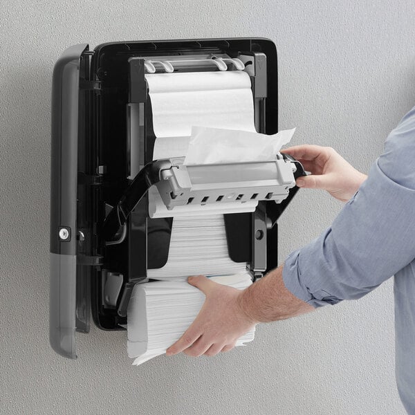 A person using a Tork paper towel dispenser in a hotel buffet.