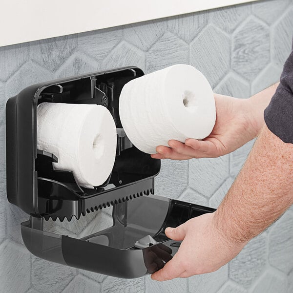 A person holding a Tork Advanced T7 coreless toilet paper roll.