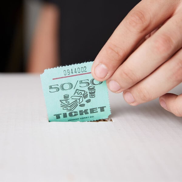 A hand holding a green 50/50 marquee raffle ticket.