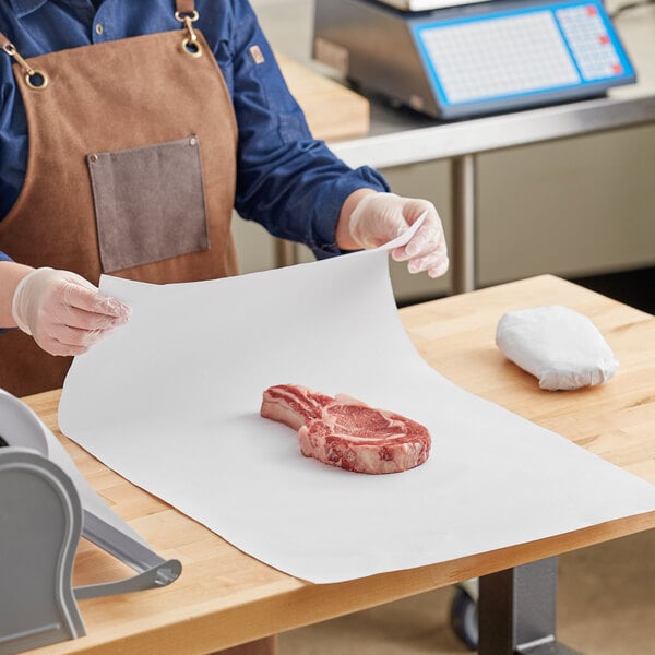 A person in a kitchen using Choice white butcher paper to wrap a piece of meat.
