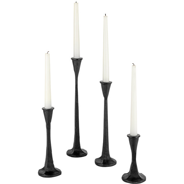 Three black candles in black candle holders on a white background.