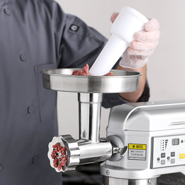 A person using a meat grinder attachment on a machine to grind meat.