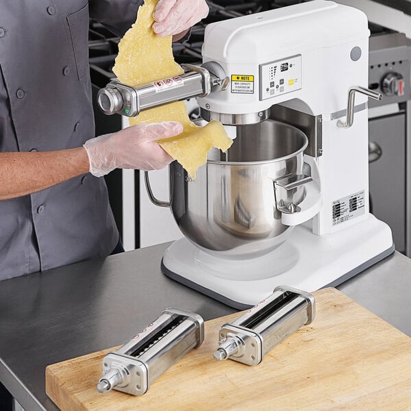 A chef using an Avantco pasta roller and cutter attachment kit on a silver and black Avantco mixer.