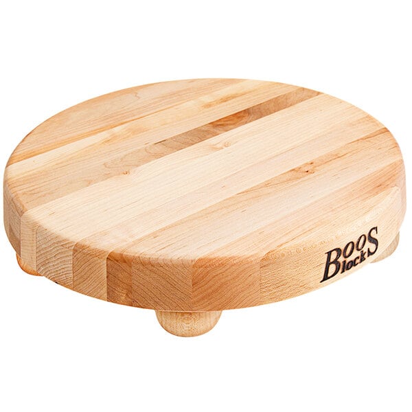 A round John Boos maple wood cutting board with bun feet.