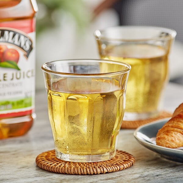 A glass of Musselman's apple juice next to a plate of croissants.
