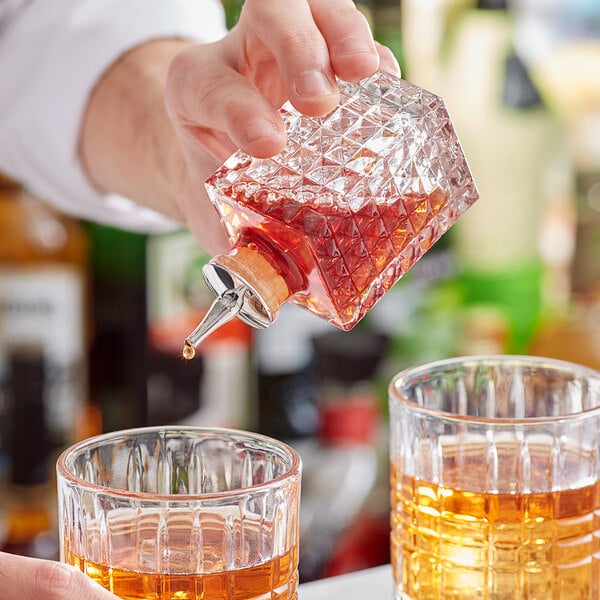 A bartender pouring Barfly bitters from a bottle into a glass.
