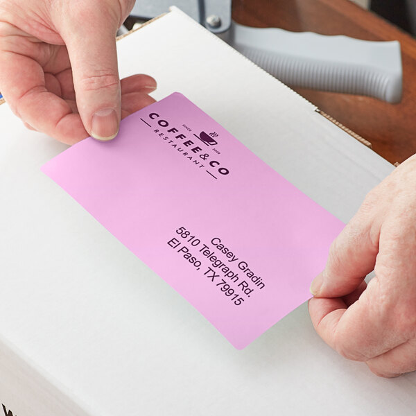 A person using a Lavex purple thermal label on a piece of paper.
